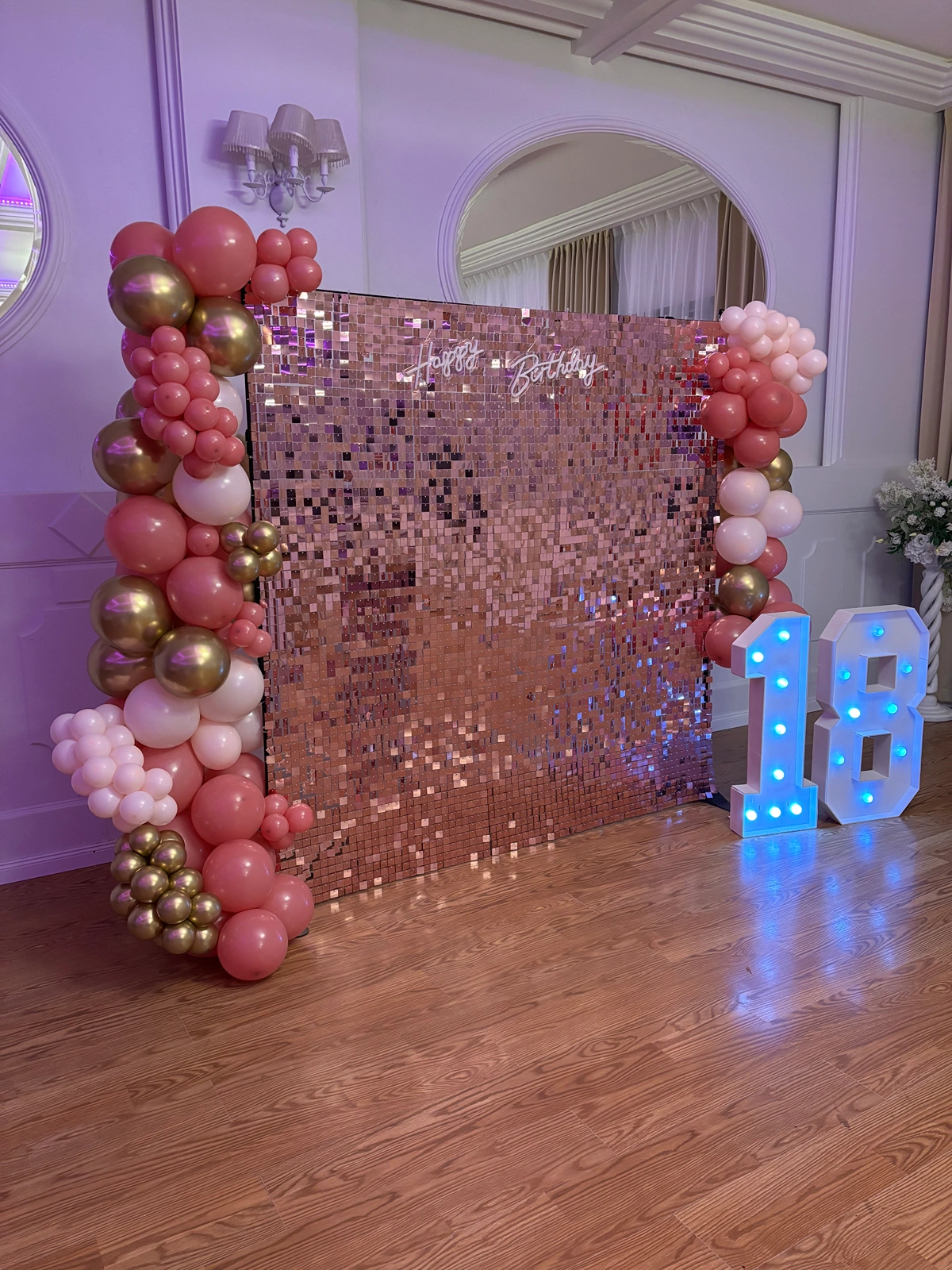 Neon Happy Birthday na tle różowych cekinów i girlandy balonowej na osiemnastkę